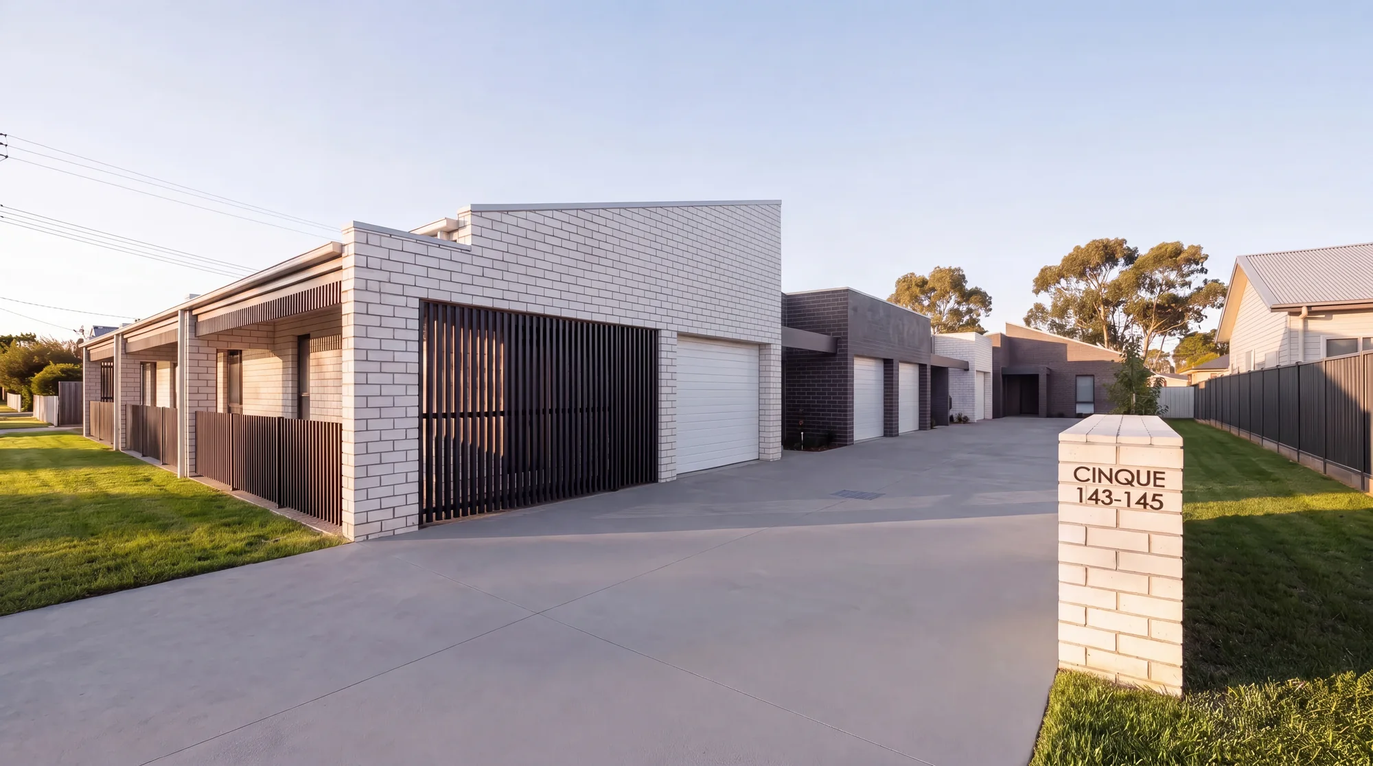 Attached single-storey Made SDA villas in varied-colour brick with a shared driveway, golden hour